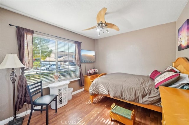 bedroom featuring a ceiling fan, light wood-style flooring, and baseboards