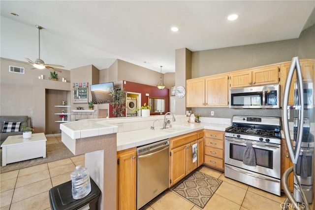 kitchen with open floor plan, a peninsula, stainless steel appliances, pendant lighting, and a sink