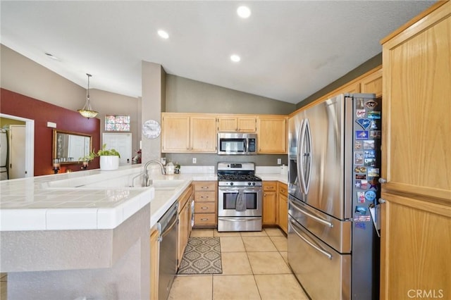 kitchen featuring a peninsula, stainless steel appliances, light brown cabinetry, pendant lighting, and a sink