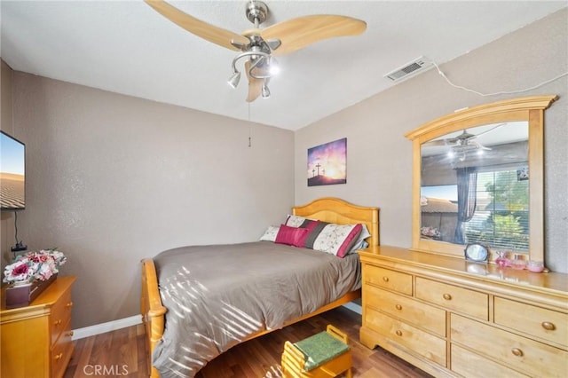 bedroom featuring a ceiling fan, dark wood-style flooring, visible vents, and baseboards