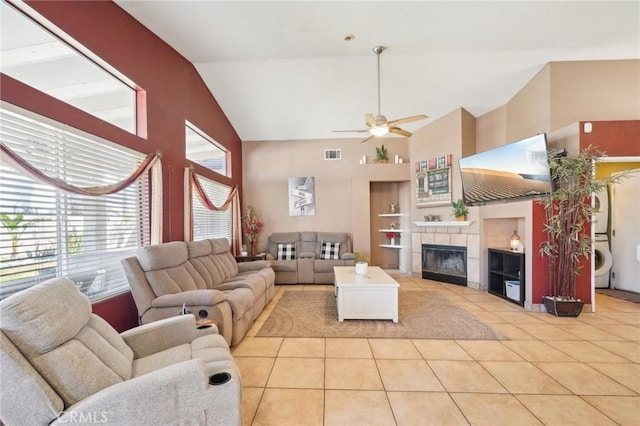 living room with light tile patterned floors, built in shelves, visible vents, stacked washing maching and dryer, and a tiled fireplace