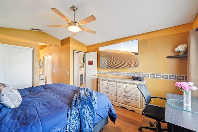 bedroom with lofted ceiling, ceiling fan, visible vents, and wood finished floors