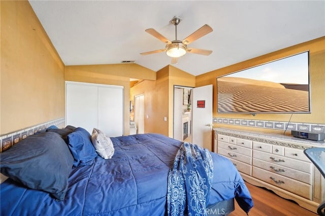 bedroom featuring ceiling fan, visible vents, vaulted ceiling, and wood finished floors