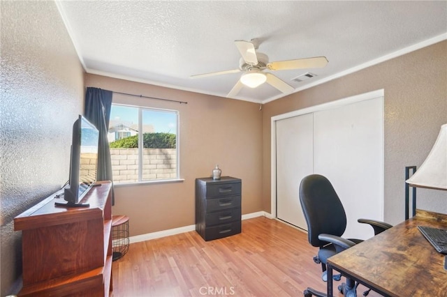 office space featuring ceiling fan, a textured wall, visible vents, baseboards, and light wood-style floors