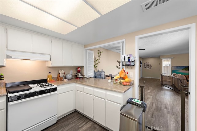 kitchen featuring dark wood-style flooring, light countertops, white cabinets, under cabinet range hood, and white gas range oven