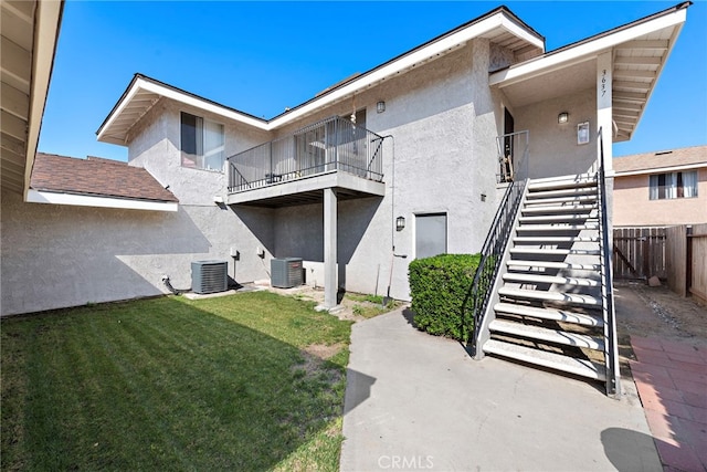 exterior space featuring a yard, stucco siding, fence, cooling unit, and stairs