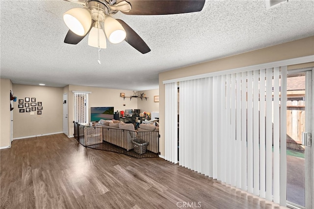 living room featuring a textured ceiling, ceiling fan, and wood finished floors