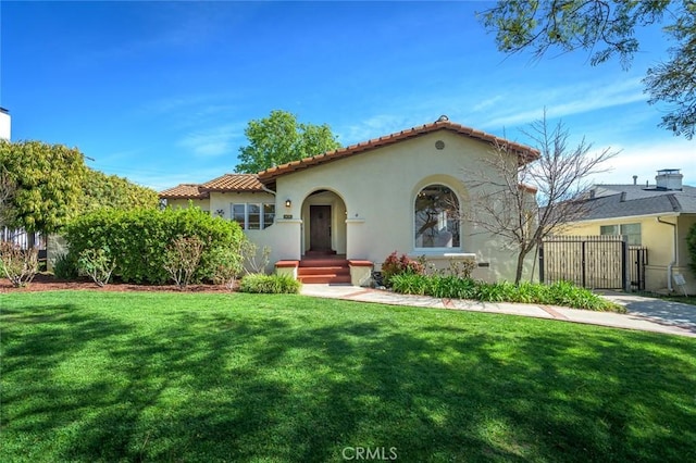 mediterranean / spanish house featuring stucco siding, a tile roof, a gate, fence, and a front yard