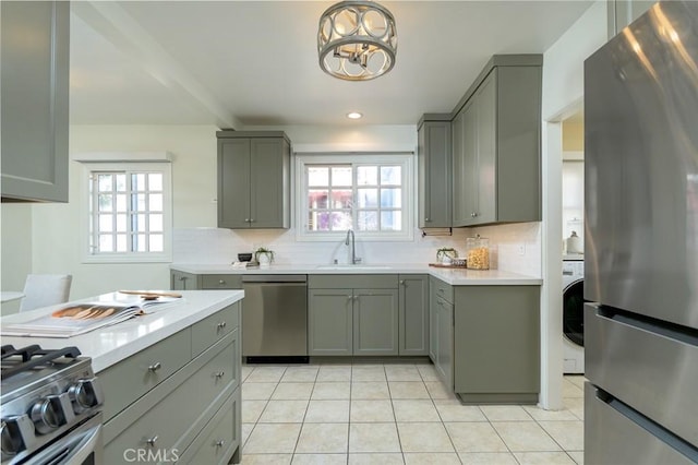 kitchen featuring light tile patterned floors, tasteful backsplash, appliances with stainless steel finishes, gray cabinetry, and a sink