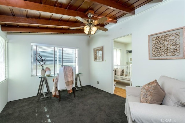 sitting room featuring a ceiling fan, carpet, wood ceiling, and beamed ceiling