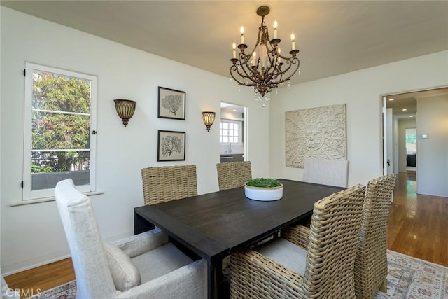 dining space featuring baseboards, a chandelier, and wood finished floors