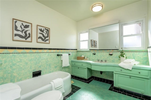 bathroom featuring a sink, tile walls, wainscoting, a soaking tub, and tile patterned floors