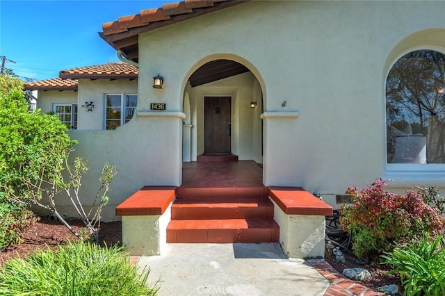 entrance to property with a tiled roof and stucco siding