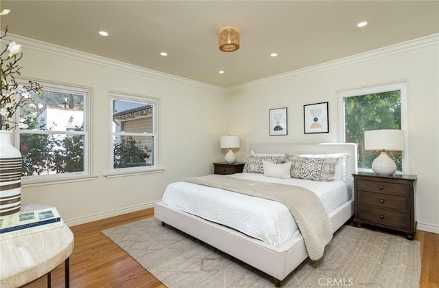 bedroom featuring baseboards, wood finished floors, and crown molding