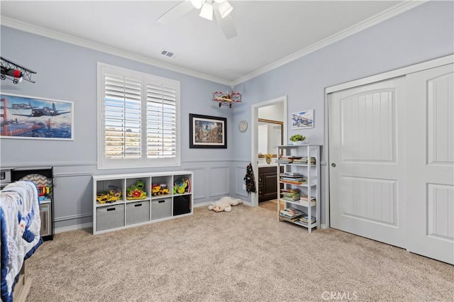 recreation room featuring a wainscoted wall, crown molding, visible vents, and carpet flooring