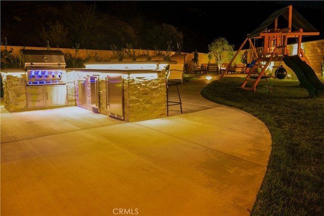 exterior space with exterior kitchen, a playground, and a grill