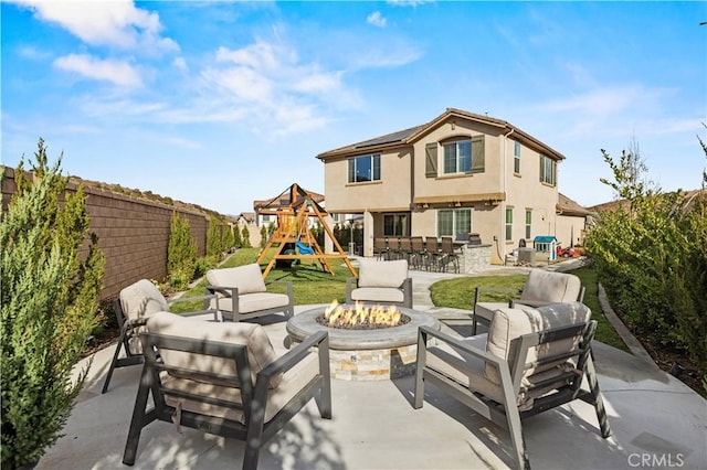 view of patio with an outdoor living space with a fire pit, a playground, and a fenced backyard