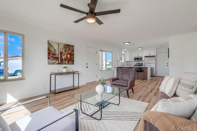 living area with ceiling fan and light wood-style flooring