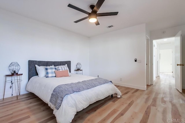 bedroom featuring a ceiling fan, visible vents, light wood-style flooring, and baseboards