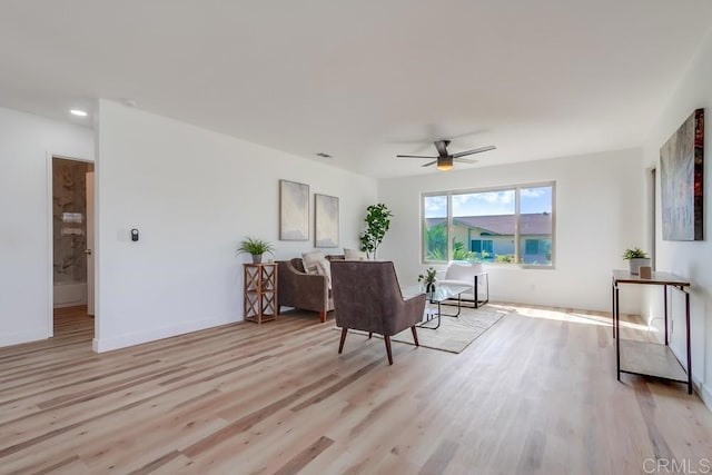 living area featuring baseboards, ceiling fan, visible vents, and light wood finished floors