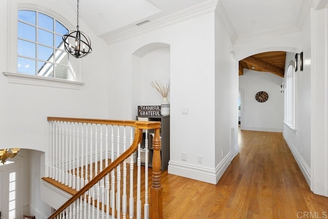 hall with visible vents, baseboards, an upstairs landing, light wood-style floors, and an inviting chandelier