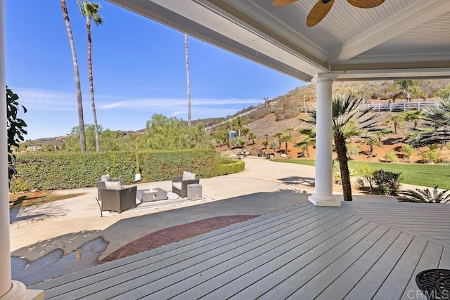 wooden terrace with outdoor lounge area, ceiling fan, and a patio