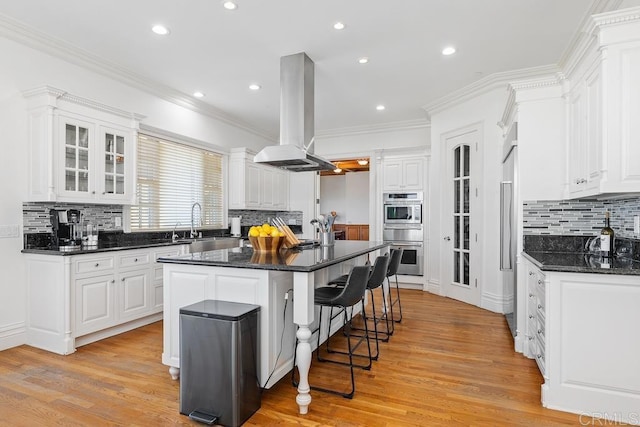 kitchen featuring glass insert cabinets, island exhaust hood, white cabinetry, and a center island