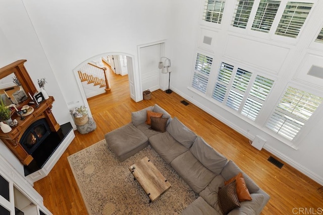 living room with visible vents, arched walkways, stairway, wood finished floors, and a high ceiling