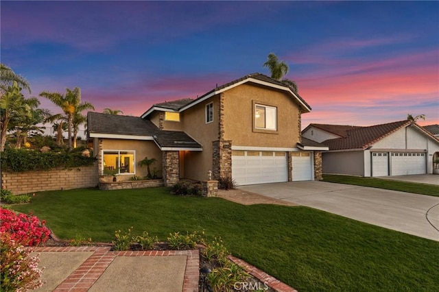 traditional home featuring stucco siding, a garage, stone siding, driveway, and a front lawn