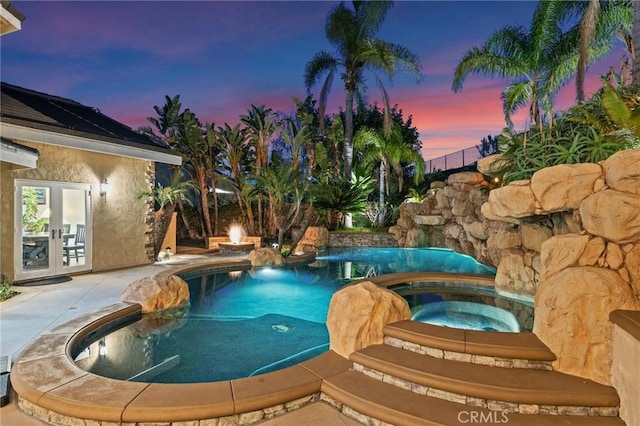 pool at dusk featuring an in ground hot tub, french doors, and an outdoor pool