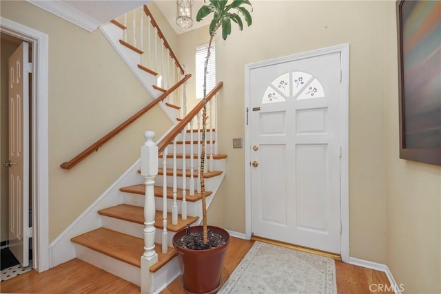 entryway with stairs, baseboards, and wood finished floors