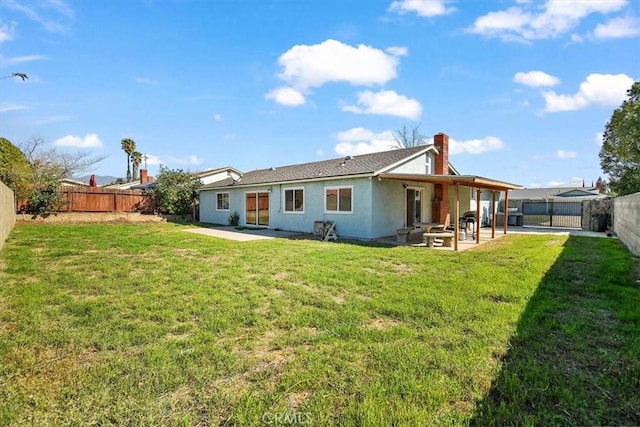 rear view of property with a patio, a lawn, a fenced backyard, and stucco siding