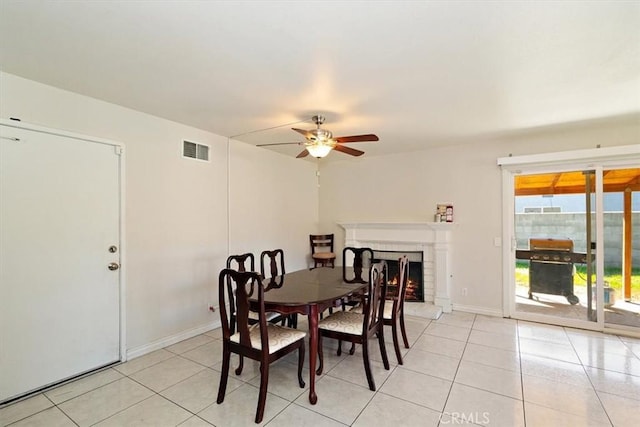 dining area with visible vents, baseboards, ceiling fan, a fireplace, and light tile patterned flooring