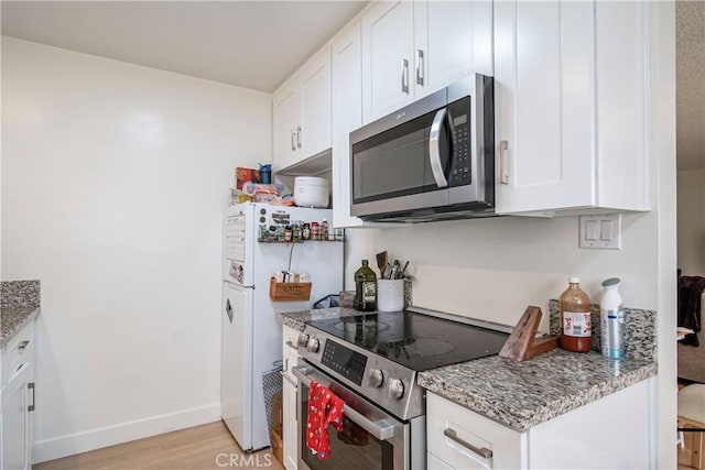 1102 Central Ave, Seal Beach, CA 90740 - kitchen with white cabinets, light wood finished floors, stainless steel appliances, light stone countertops, and baseboards