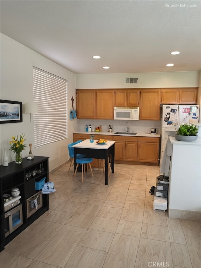 kitchen with recessed lighting, light countertops, visible vents, a sink, and white appliances