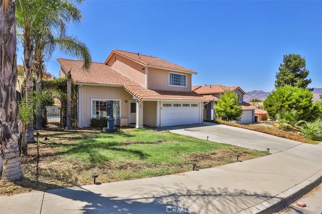 mediterranean / spanish house featuring a garage, a tile roof, fence, driveway, and a front lawn