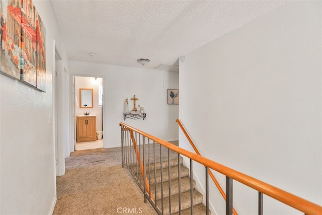 hall featuring a textured ceiling and light colored carpet