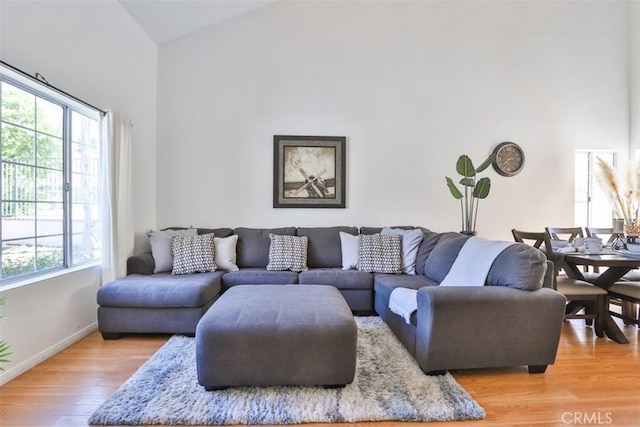 living area featuring high vaulted ceiling, wood finished floors, and baseboards