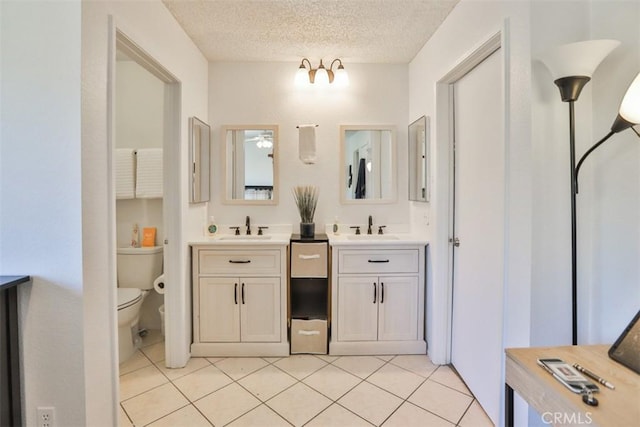 bathroom with a textured ceiling, ceiling fan, tile patterned flooring, toilet, and vanity