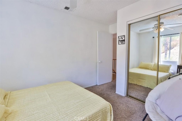 bedroom with a ceiling fan, dark colored carpet, visible vents, and a textured ceiling