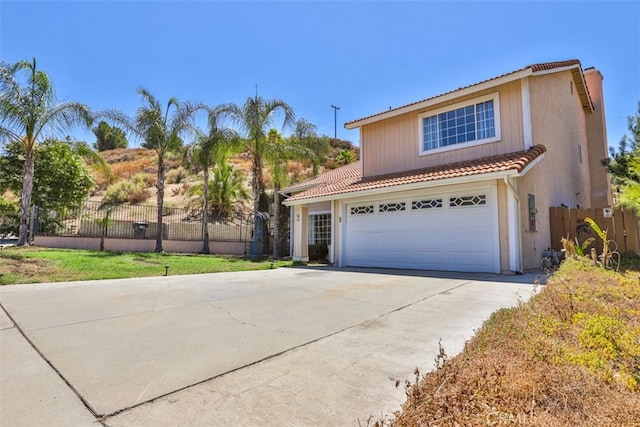 mediterranean / spanish-style house with concrete driveway, fence, and a tiled roof