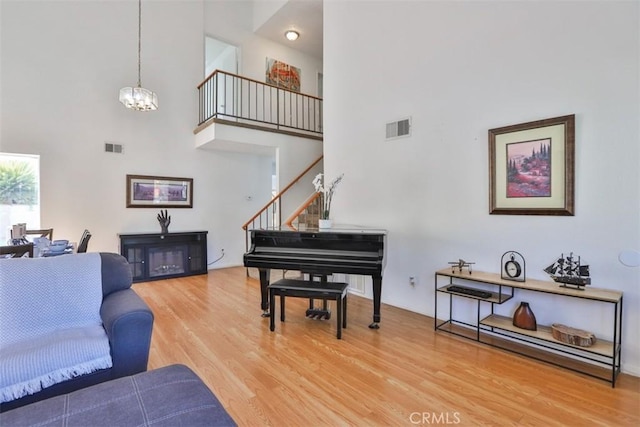 living room with stairs, visible vents, a chandelier, and wood finished floors