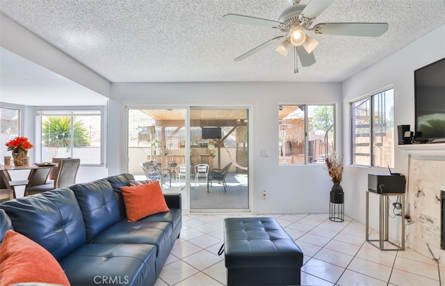 living room featuring ceiling fan, a textured ceiling, and light tile patterned floors