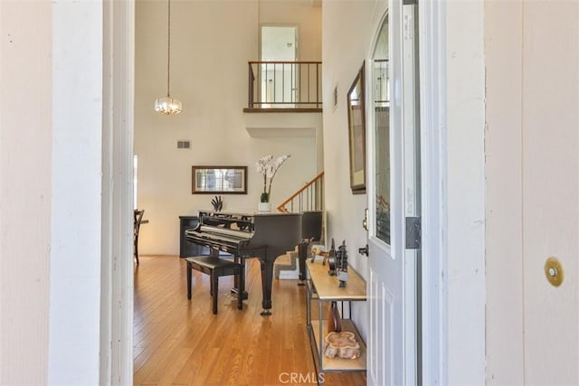 living area with stairs, wood finished floors, a towering ceiling, and a chandelier