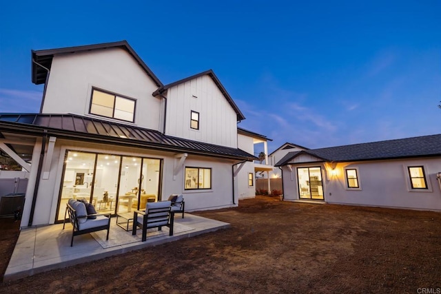 rear view of house featuring metal roof, a standing seam roof, and a patio area