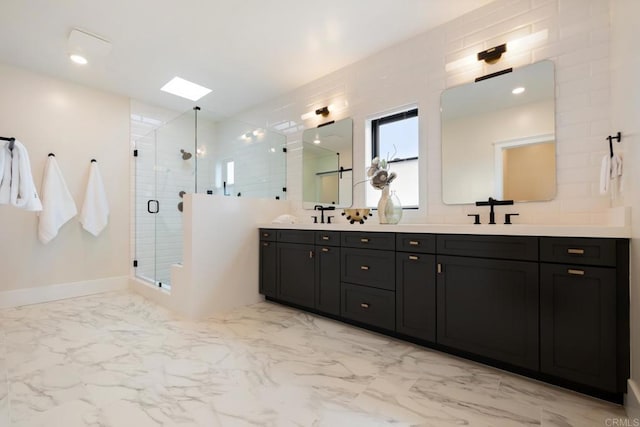 full bath with a skylight, marble finish floor, double vanity, a stall shower, and a sink