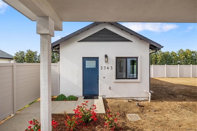 view of exterior entry featuring fence and stucco siding