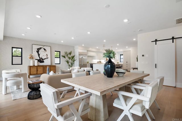 dining room featuring a barn door, recessed lighting, visible vents, and light wood-style floors