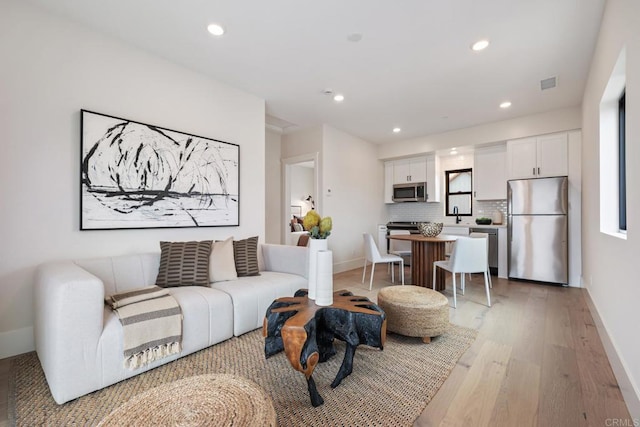 living room featuring recessed lighting, visible vents, baseboards, and wood finished floors