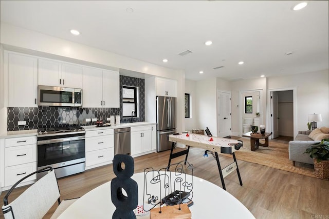 kitchen with appliances with stainless steel finishes, white cabinets, light countertops, and visible vents